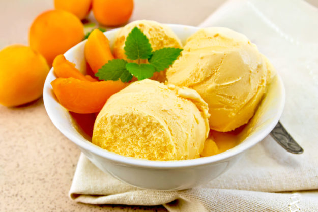 Ice cream apricot in bowl with spoon on napkin